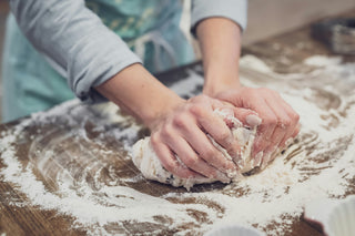 Person kneading dough on a floured wooden surface
